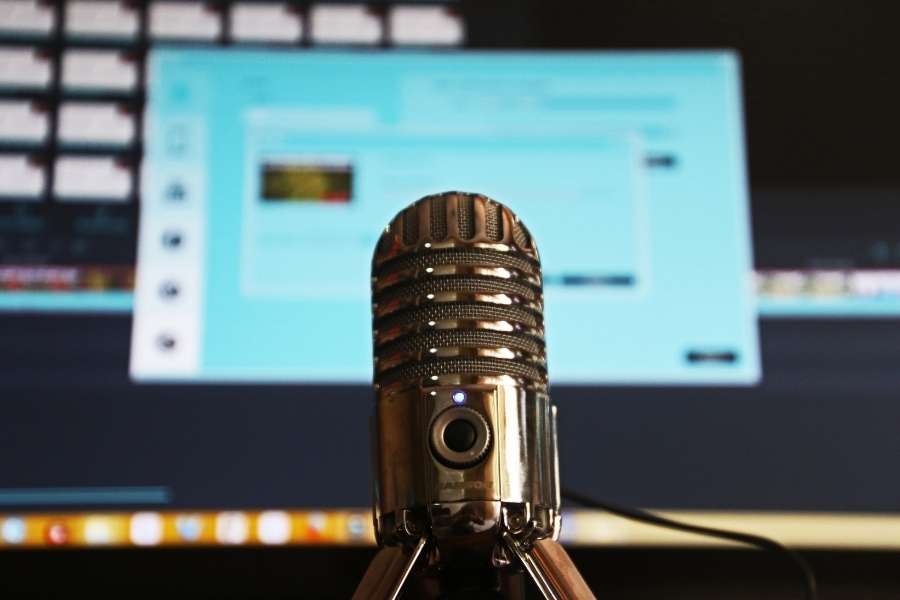 Un microphone rétro en métal sur trépied devant un écran d'ordinateur.