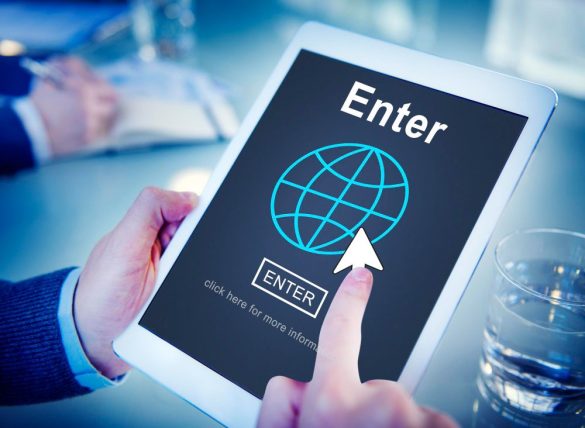 Une personne tenant une tablette affichant un globe numérique et un bouton Enter, idéale pour consulter un comparatif registrar.